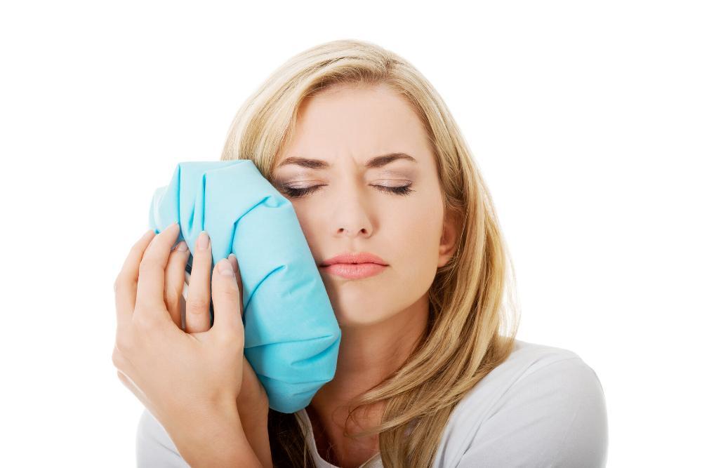Woman holding ice pack on jaw from tooth pain