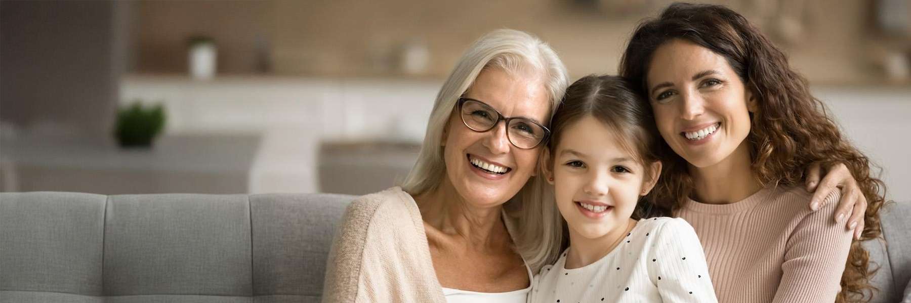 mother, grandmother, and daughter smiling on a couch 