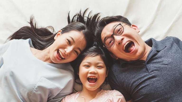 mom, dad, and daughter smiling