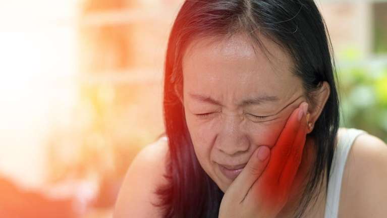 woman holding her jaw from tooth pain during a dental emergency
