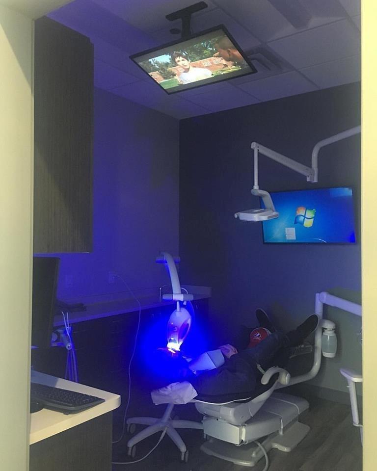TV above dental chair while patient gets teeth whitened 